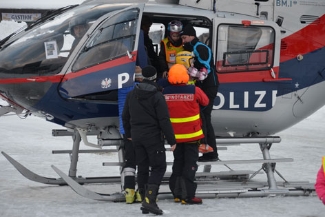 Skifahrer steigen in Hubschrauber ein