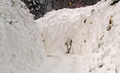 Straße begrenzt von hohen Schneewänden einer Lawine