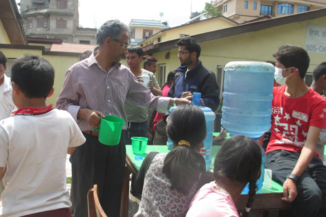 Im SOS-Kinderdorf Jorpati bei Kathmandu verteilt Dorfleiter Rabin Nepal (Bildmitte) mit Mitarbeitern und Jugendlichen Trinkwasser und organisiert auch Nahrung, Medikamente und Zelte