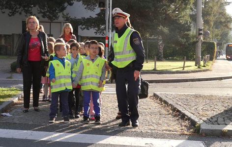 Polizist führt Kinder über Schutzweg