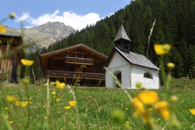 Ober- und Unterstalleralm Bild 8: Kapelle und Hütte im Hintergrund mit Bergen und im Vordergrund Blumen