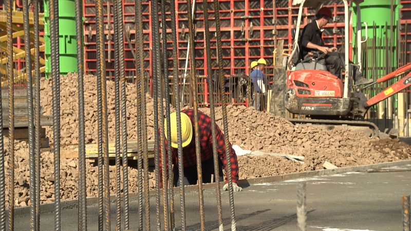 Arbeiter auf Baustelle, im Hintergrund Bagger