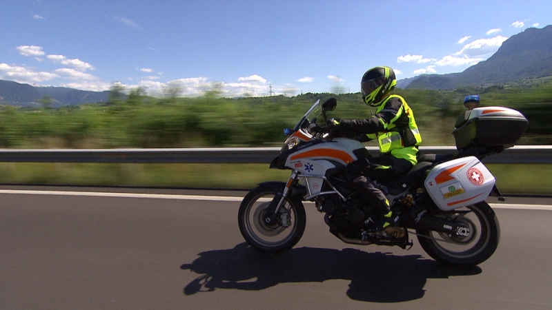 Ein Sanitäter des Weißen Kreuzes mit gelber Warnweste unterwegs auf dem Motorrad