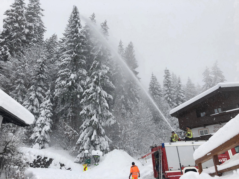 Feuerwehr spritzt Schnee von Bäumen